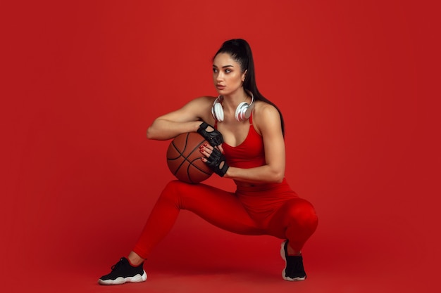 Belle jeune athlète féminine pratiquant sur le portrait monochrome de mur rouge