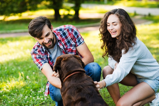 Belle jeune couple jouant avec leur chien dans le jardin