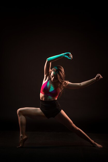 Belle jeune danseuse dansant sur le mur noir