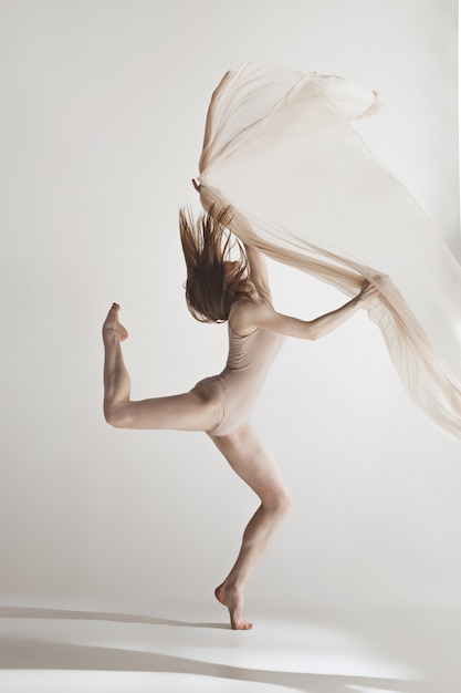 Belle jeune danseuse en maillot de bain beige danse