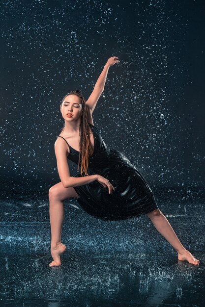 La belle jeune danseuse moderne dansant sous les gouttes d'eau