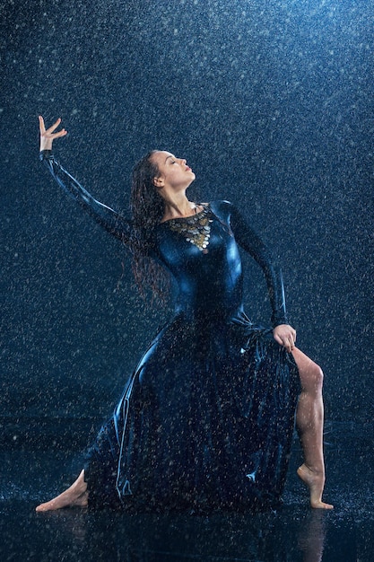 La belle jeune danseuse moderne danse sous des gouttes d'eau