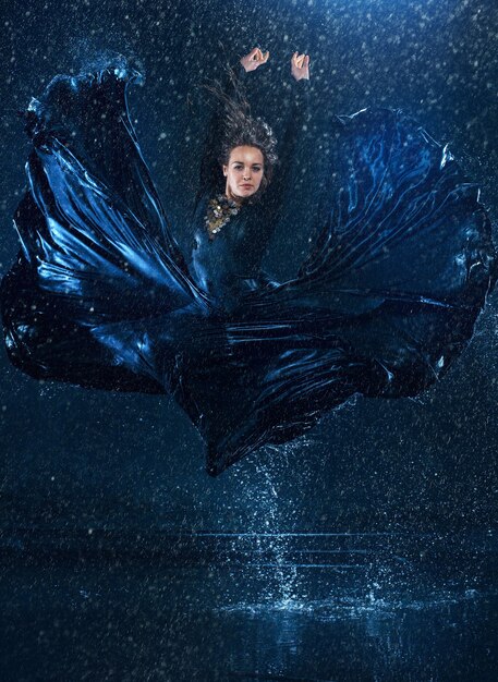 La belle jeune danseuse moderne danse sous des gouttes d'eau