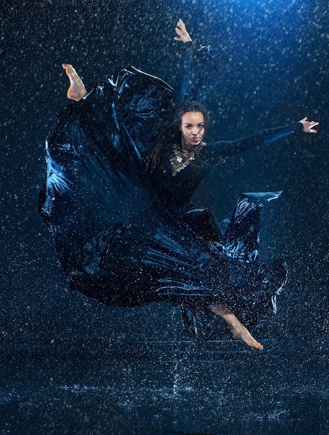 La belle jeune danseuse moderne danse sous des gouttes d'eau