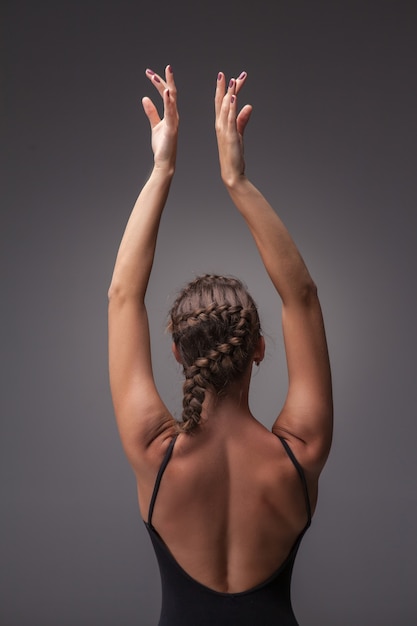 La belle jeune danseuse de style moderne posant sur un fond gris studio. vue de dos