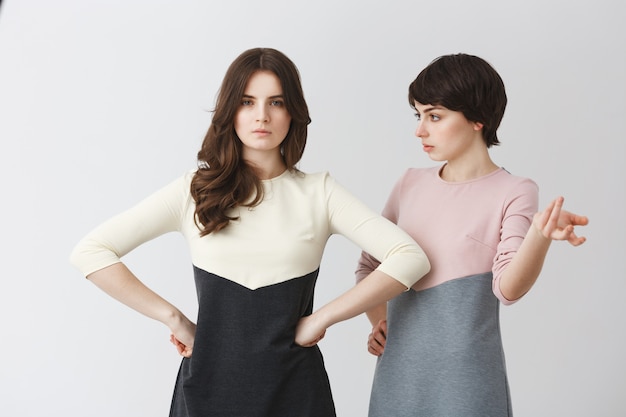 Belle jeune étudiante lesbienne discutant avec sa belle petite amie aux cheveux longs de la meilleure pose pour une photo dans un photomaton.