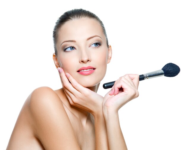 Belle jeune femme adulte tient la brosse de maquillage pour appliquer du rouge ou de la poudre. Top model