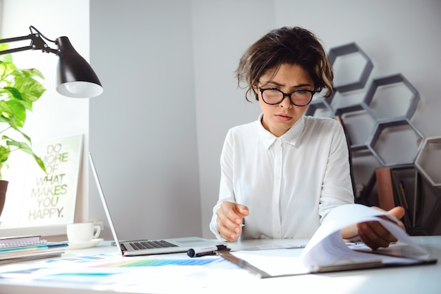 Belle jeune femme d'affaires assis sur le lieu de travail au bureau.