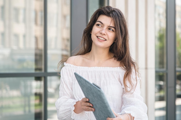 Belle jeune femme d'affaires avec un ordinateur portable à l'extérieur