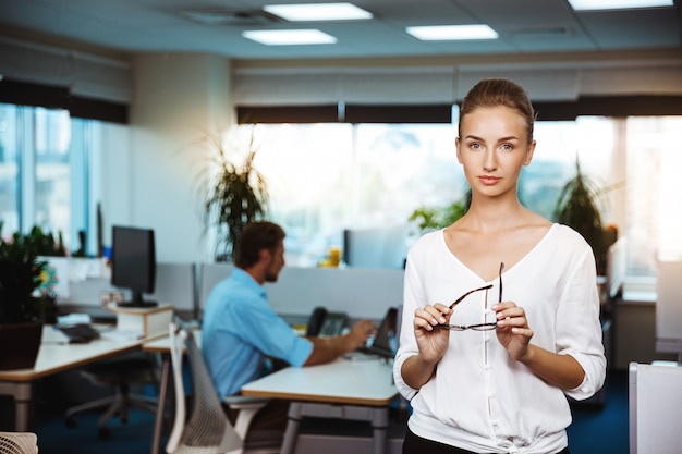 Belle jeune femme d'affaires réussie souriant, posant, sur le bureau