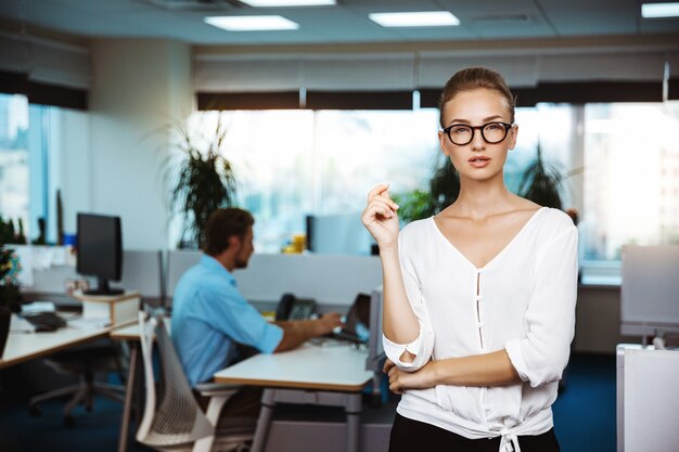 Belle jeune femme d'affaires réussie souriant, posant, sur le bureau