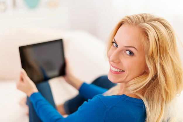 Belle jeune femme à l'aide de tablette numérique sur canapé