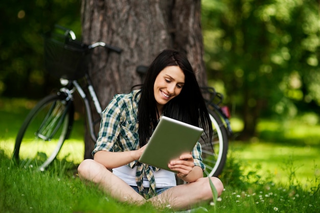 Belle jeune femme à l'aide de tablette numérique à l'extérieur