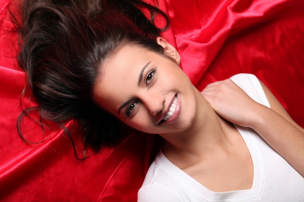 Belle jeune femme allongée en soie rouge, vue de dessus