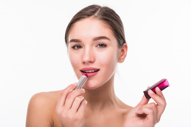 Photo gratuite belle jeune femme appliquant le rouge à lèvres sur les lèvres isolées sur le mur blanc.