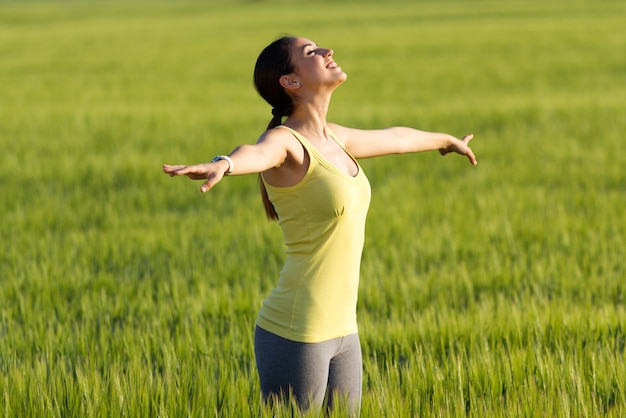 Belle jeune femme appréciant le printemps debout dans un champ de céréales