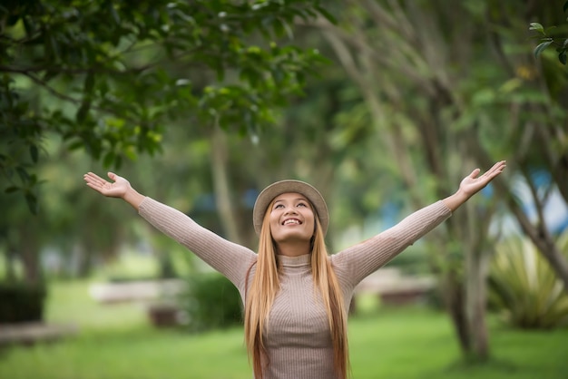 Photo gratuite belle jeune femme appréciant son temps à l'extérieur en levant les mains dans le parc