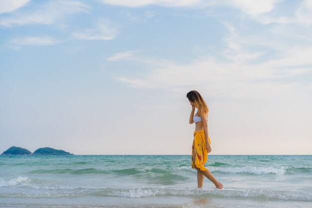 Belle jeune femme asiatique heureuse se détendre à pied sur la plage près de la mer.