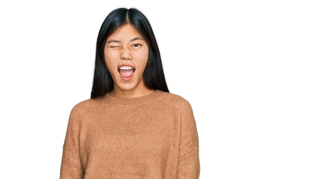 Photo gratuite belle jeune femme asiatique portant un pull d'hiver décontracté en regardant la caméra avec une expression sexy visage joyeux et heureux