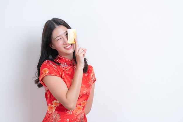 Belle jeune femme asiatique porter une robe traditionnelle chinoise rouge tenant une carte de crédit pour le nouvel an chinois avec un fond blanc