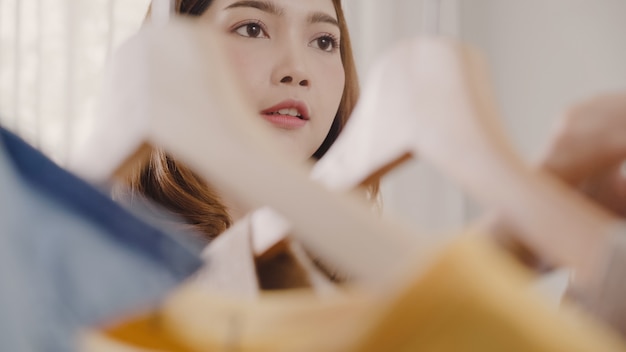 Belle jeune femme asiatique séduisante choisissant ses vêtements de costume de mode dans le placard à la maison