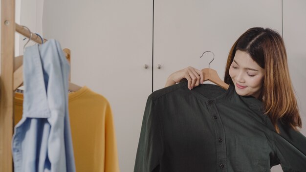 Belle jeune femme asiatique séduisante choisissant ses vêtements de costume de mode dans le placard à la maison