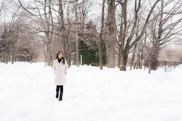 Belle jeune femme asiatique souriante heureuse de voyager dans la neige en hiver