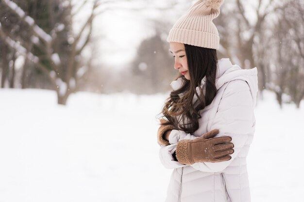 Belle jeune femme asiatique souriante heureuse de voyager dans la neige en hiver