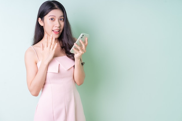 Belle jeune femme asiatique tenant un smartphone sur fond vert