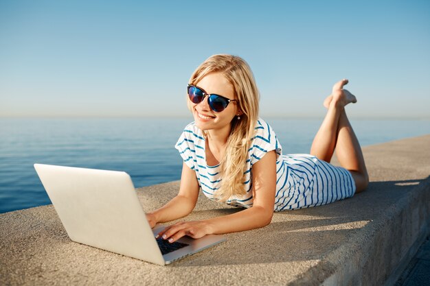 Belle jeune femme assise sur la plage avec ordinateur portable