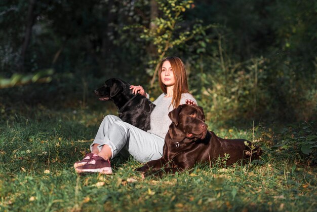 Belle jeune femme assise avec ses animaux de compagnie dans le parc