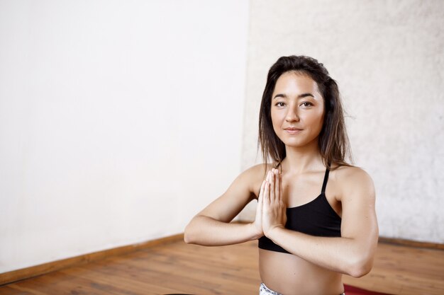 Belle jeune femme athlétique pratiquant le yoga en salle sur tapis rouge