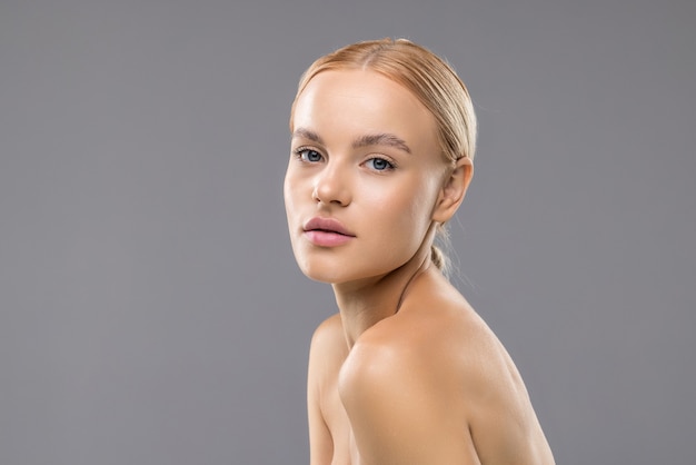 Belle jeune femme aux cheveux longs à la mode naturelle composent un salon de spa cosmétique isolé sur fond gris