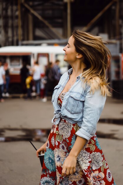 Une belle jeune femme aux cheveux longs avec un verre de café sourit et rit.