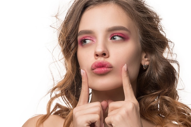 Belle jeune femme aux longs cheveux soyeux ondulés, maquillage naturel en regardant la caméra