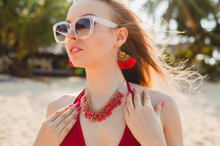 Photo gratuit belle jeune femme blonde se faire bronzer sur la plage en maillot de bain rouge, lunettes de soleil