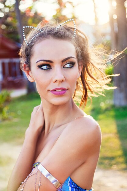 Belle jeune femme bronzée sexy posant dans un pays tropical chaud pendant ses vacances. Porter un maquillage lumineux, des couleurs ensoleillées.