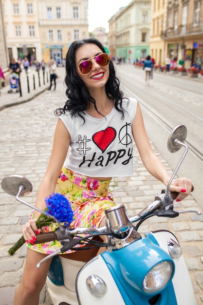 Photo gratuite belle jeune femme à cheval sur la rue de la ville de moto