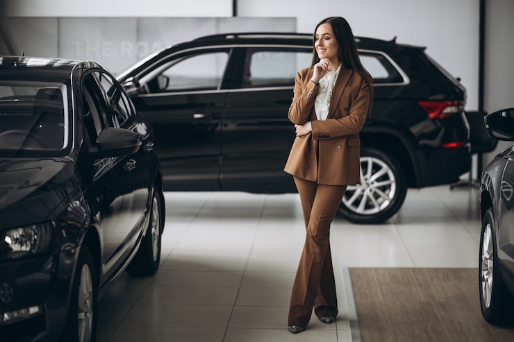 Photo gratuit belle jeune femme choisissant la voiture dans une salle d'exposition de voiture