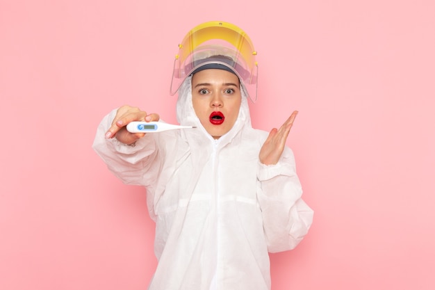 Belle jeune femme en costume blanc spécial et dispositif de maintien de casque jaune sur rose