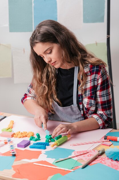 Belle jeune femme couper l&#39;argile avec un cutter sur table