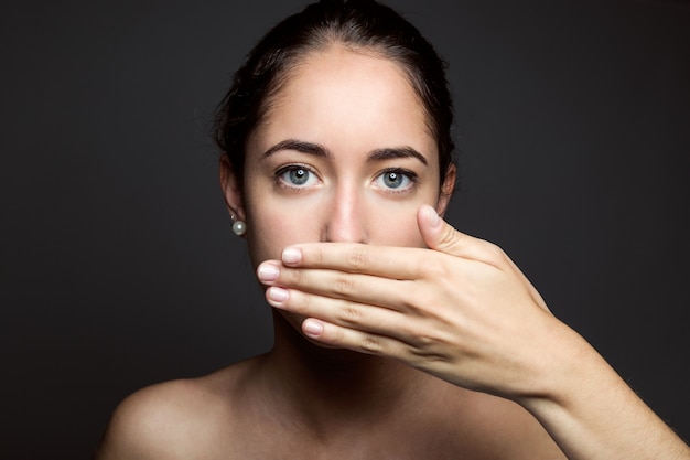 Photo gratuite belle jeune femme couvrant sa bouche à la main. isolé.