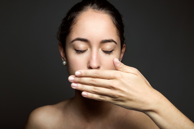 Belle jeune femme couvrant sa bouche à la main. Isolé.