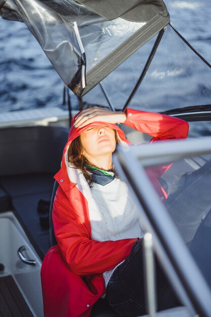 belle jeune femme dans un imperméable rouge monte un yacht privé. Stockholm, Suède