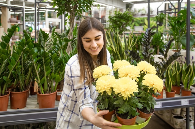 Belle jeune femme dans un magasin de fleurs et choisir des fleurs. Le concept de jardinage et de fleurs.