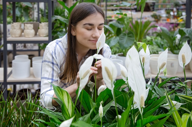 Belle jeune femme dans un magasin de fleurs et choisir des fleurs.