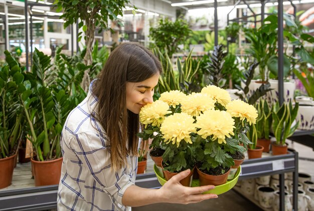 Belle jeune femme dans un magasin de fleurs et choisir des fleurs.