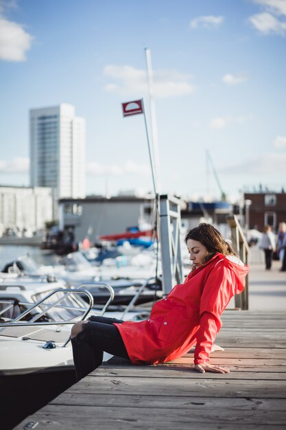 Belle jeune femme dans un manteau rouge dans le port de yacht. Stockholm, Suède