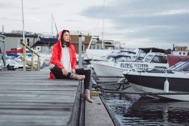 Belle jeune femme dans un manteau rouge dans le port de yacht. Stockholm, Suède