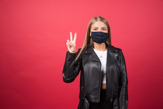 Belle jeune femme dans un masque médical montrant le signe de la victoire